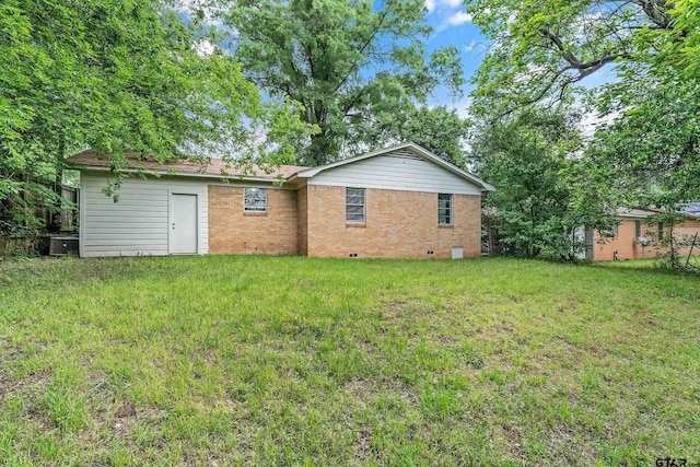 back of house featuring crawl space, a lawn, and brick siding
