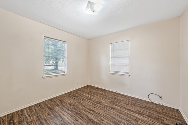 unfurnished room with dark wood-style flooring and baseboards