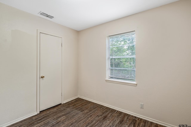empty room featuring dark wood-type flooring and baseboards