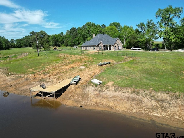 view of storm shelter featuring fence, a water view, and a yard
