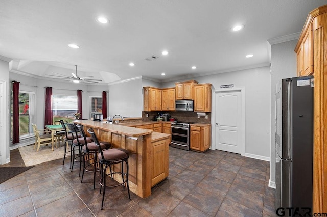 kitchen with crown molding, baseboards, a kitchen bar, a peninsula, and appliances with stainless steel finishes