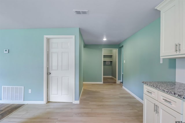 kitchen featuring light stone counters, light hardwood / wood-style floors, and white cabinets