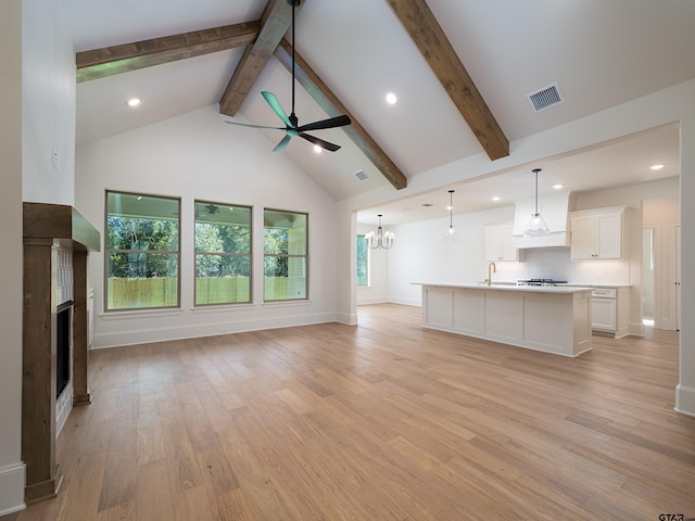 unfurnished living room featuring beamed ceiling, light hardwood / wood-style floors, ceiling fan with notable chandelier, and high vaulted ceiling