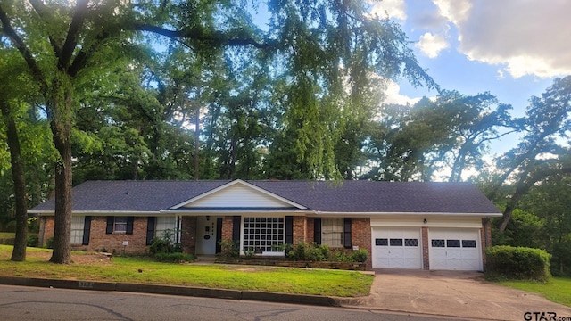 ranch-style home featuring an attached garage, brick siding, concrete driveway, and a front yard