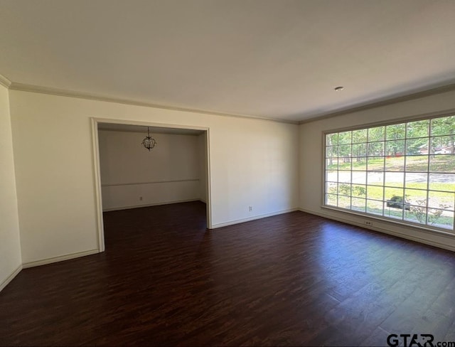 empty room with dark wood-style flooring, baseboards, and ornamental molding