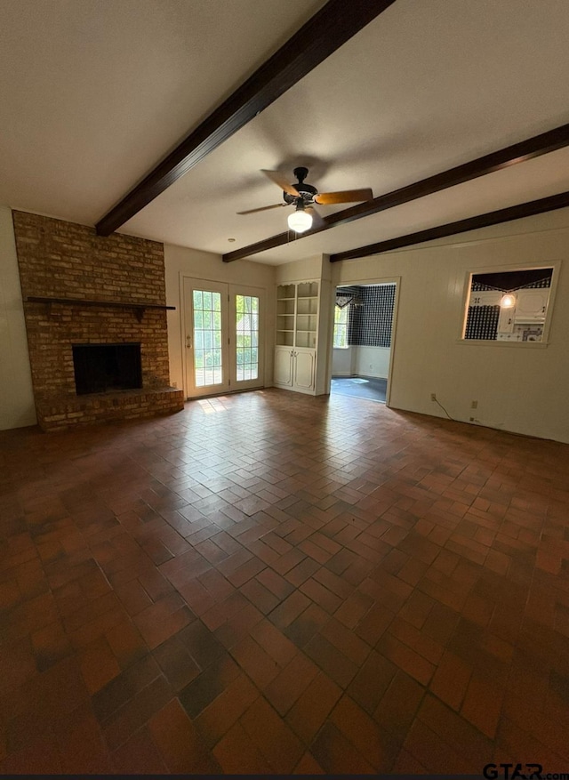 unfurnished living room featuring beamed ceiling, ceiling fan, brick patterned floors, and a fireplace