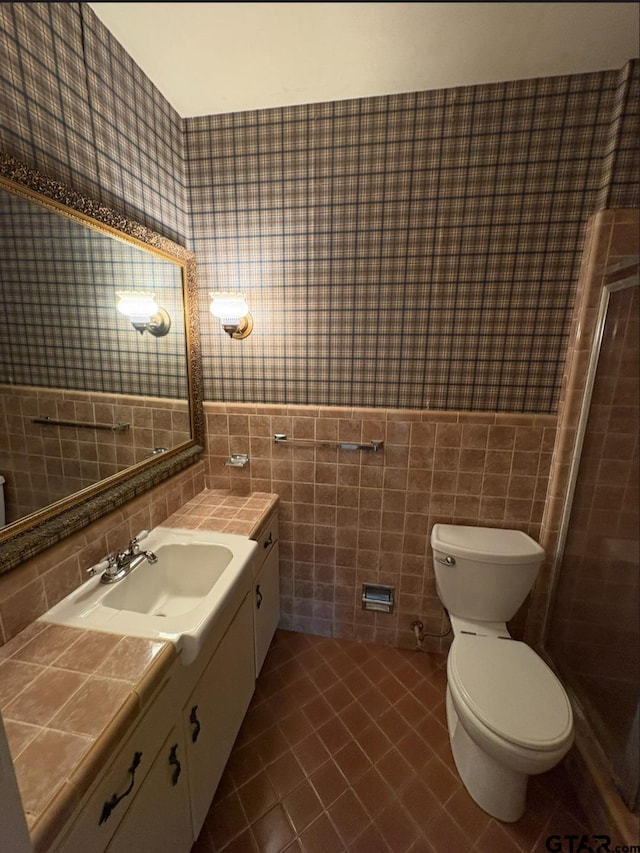 full bath with tile walls, tile patterned flooring, toilet, vanity, and a shower