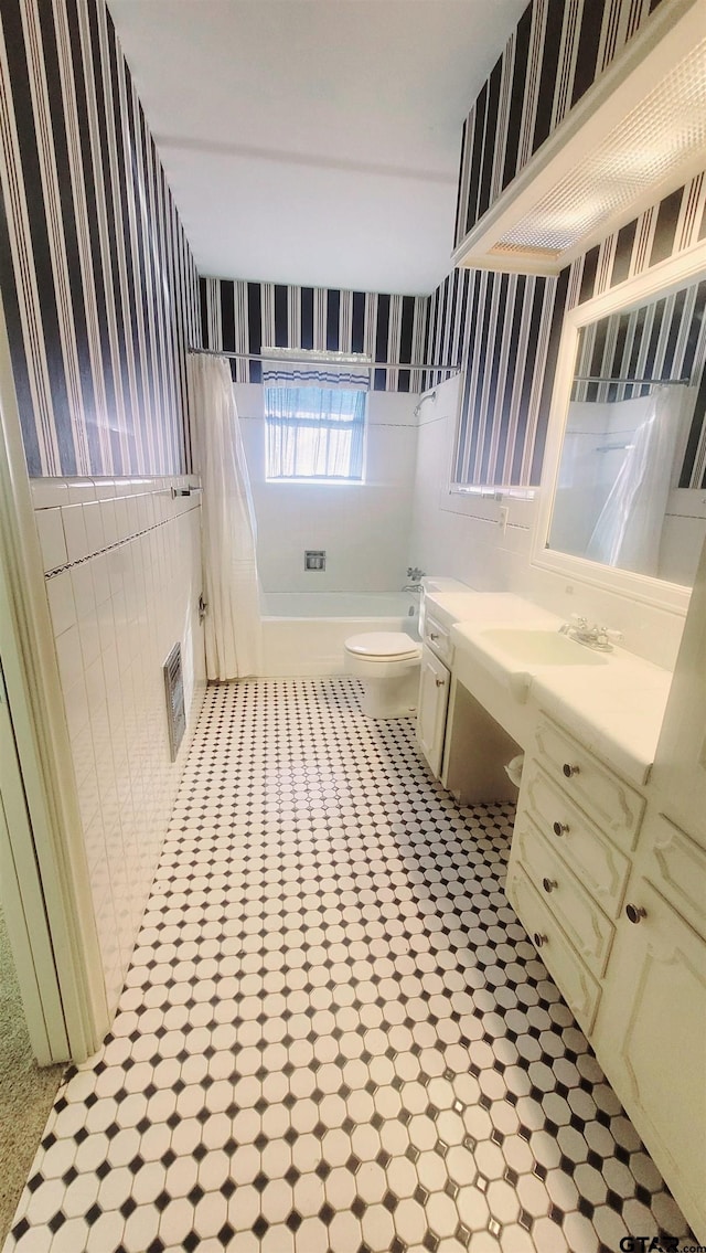 bathroom with wallpapered walls, toilet, vanity, and shower / bath combination