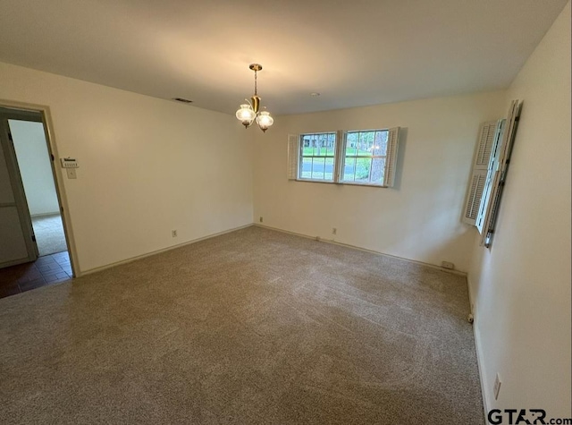 carpeted spare room with a chandelier and baseboards