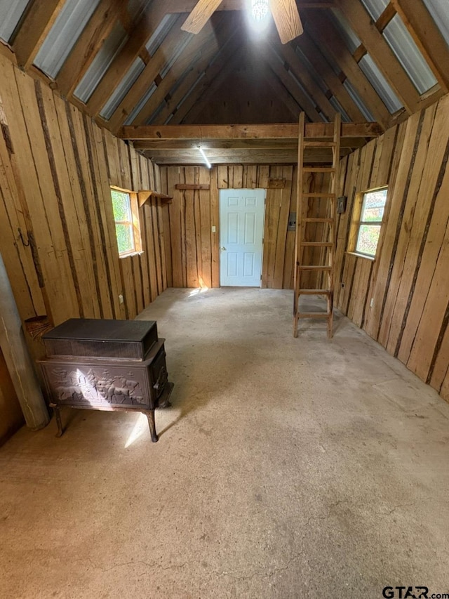miscellaneous room featuring lofted ceiling, healthy amount of natural light, carpet, and a wood stove