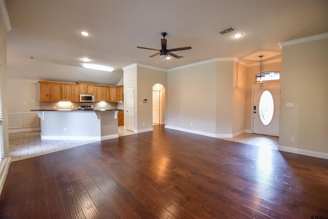 unfurnished living room with wood-type flooring, ornamental molding, and ceiling fan