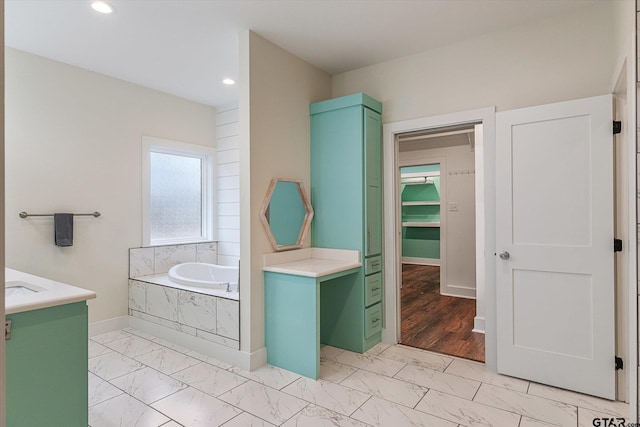 bathroom with vanity and tiled bath