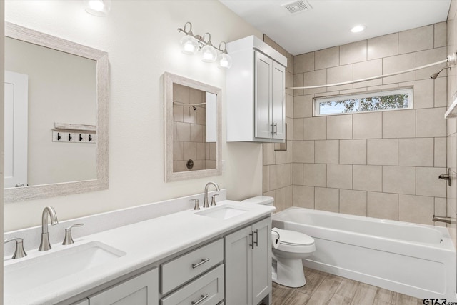 full bathroom featuring vanity, toilet, wood-type flooring, and tiled shower / bath