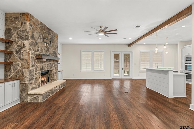 unfurnished living room with ceiling fan, sink, dark wood-type flooring, beamed ceiling, and a fireplace