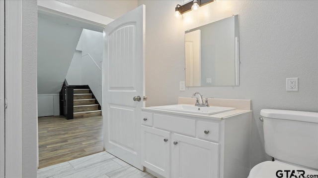 bathroom with hardwood / wood-style floors, vanity, and toilet