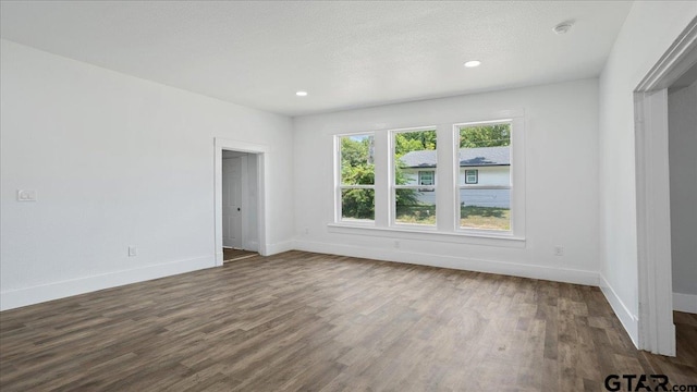 empty room featuring a textured ceiling and dark hardwood / wood-style floors