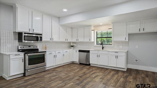 kitchen with tasteful backsplash, appliances with stainless steel finishes, sink, white cabinets, and dark wood-type flooring