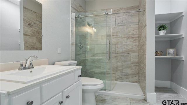 bathroom featuring toilet, vanity, and a shower with door