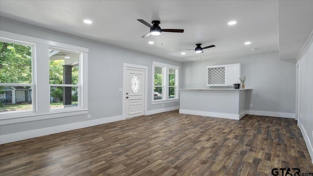 unfurnished living room featuring dark wood-type flooring, a wealth of natural light, ceiling fan, and crown molding