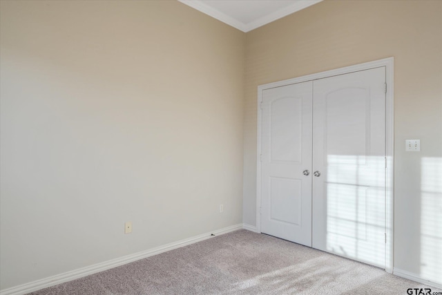 unfurnished bedroom featuring crown molding, a closet, baseboards, and light colored carpet