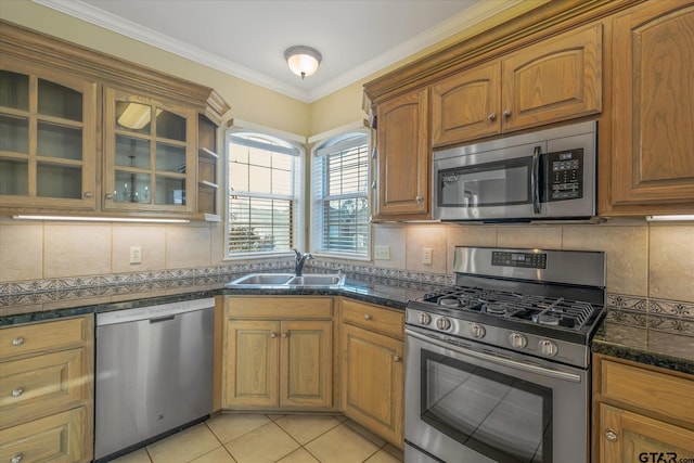 kitchen with a sink, appliances with stainless steel finishes, tasteful backsplash, glass insert cabinets, and crown molding