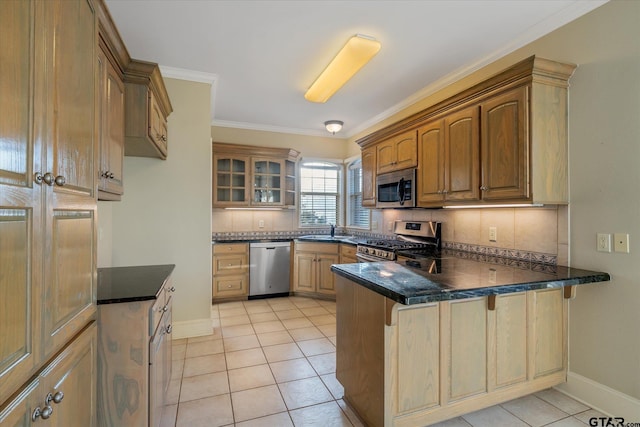 kitchen featuring light tile patterned floors, a peninsula, a sink, appliances with stainless steel finishes, and glass insert cabinets