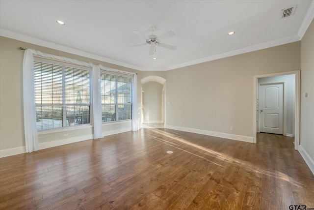 empty room featuring crown molding, arched walkways, visible vents, and dark wood finished floors