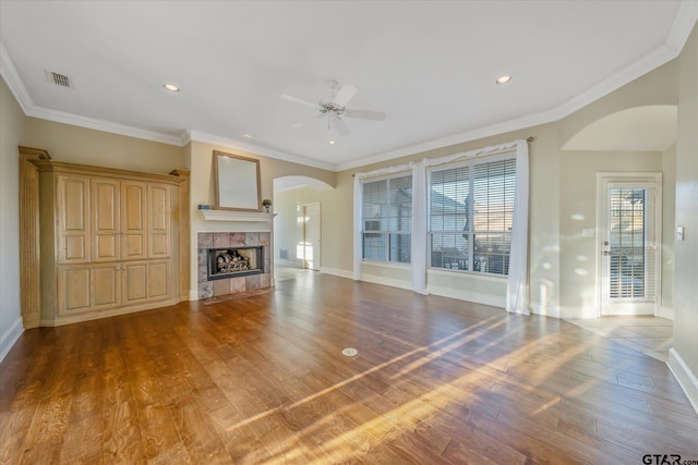 unfurnished living room with crown molding, visible vents, a fireplace, and wood finished floors