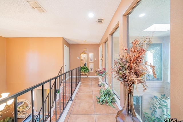 corridor featuring light tile patterned flooring and a textured ceiling