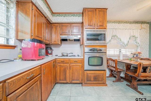 kitchen with a textured ceiling, plenty of natural light, light tile patterned floors, and stainless steel appliances