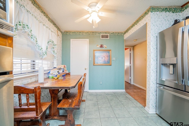 tiled dining room with ceiling fan and a textured ceiling