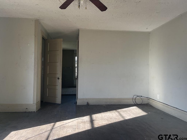 spare room featuring a textured ceiling, a ceiling fan, and baseboards