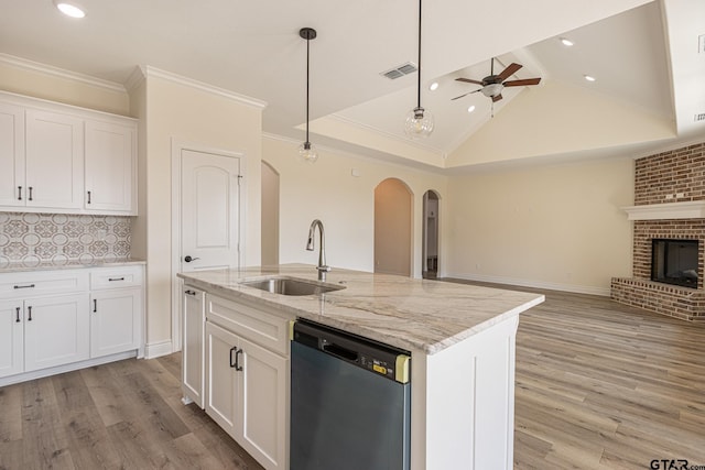 kitchen featuring sink, dishwasher, light stone counters, an island with sink, and white cabinets