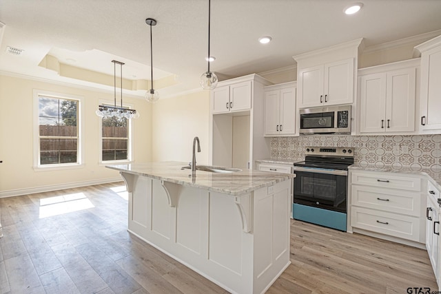 kitchen featuring stainless steel appliances, a center island with sink, and white cabinets