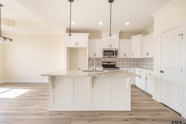 kitchen featuring white cabinetry, light stone counters, an island with sink, pendant lighting, and stainless steel appliances