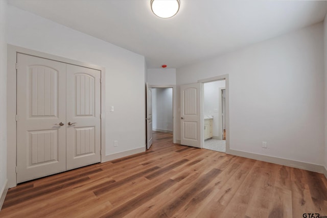 unfurnished bedroom featuring ensuite bath, hardwood / wood-style flooring, and a closet