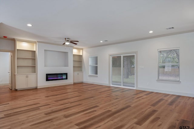 unfurnished living room featuring ceiling fan, light hardwood / wood-style flooring, built in shelves, and ornamental molding