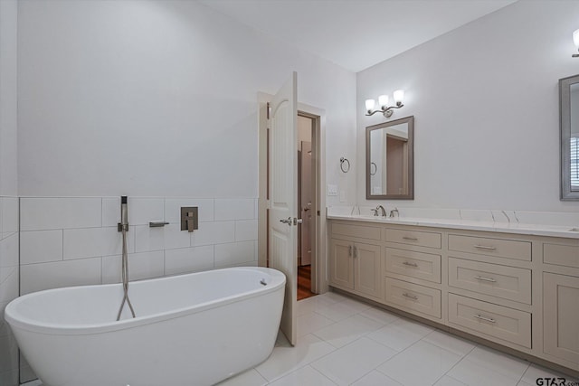 bathroom featuring tile walls, a tub, vanity, and tile patterned floors