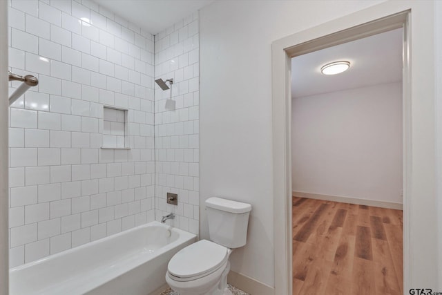 bathroom with toilet, tiled shower / bath combo, and wood-type flooring