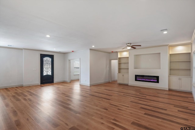 unfurnished living room featuring built in features, wood-type flooring, ceiling fan, and crown molding