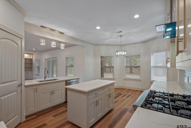 kitchen with ornamental molding, a kitchen island, pendant lighting, sink, and hardwood / wood-style flooring