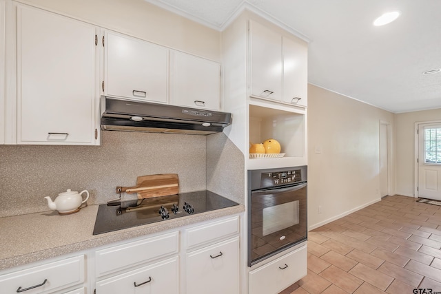 kitchen featuring under cabinet range hood, decorative backsplash, black appliances, light countertops, and white cabinets