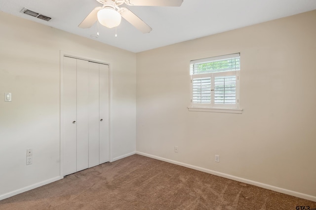 unfurnished bedroom featuring a closet, a ceiling fan, visible vents, carpet, and baseboards