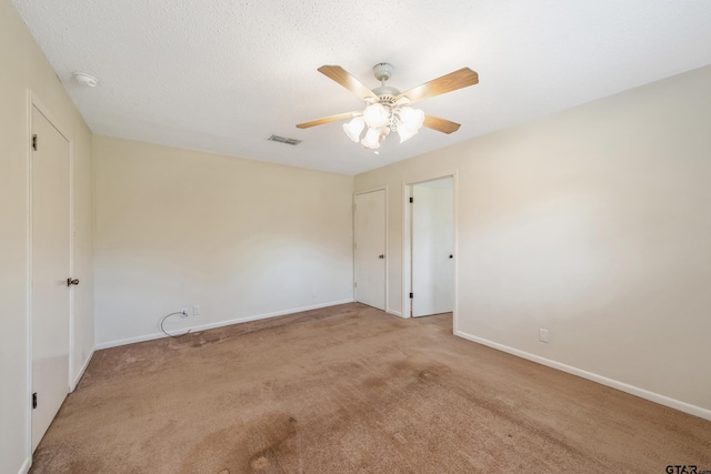 spare room featuring baseboards, visible vents, ceiling fan, and carpet floors