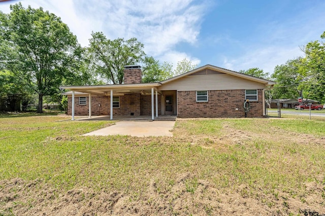 rear view of property featuring a patio area, a yard, a chimney, brick siding, and fence
