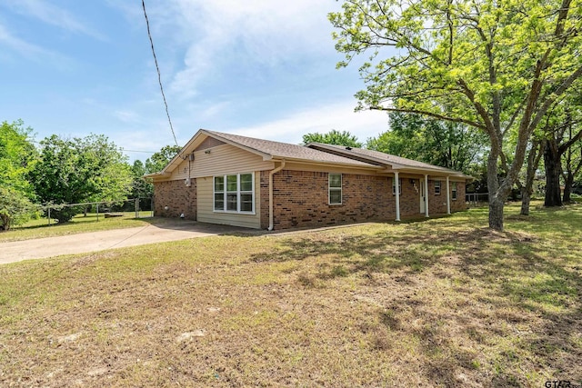 view of home's exterior featuring a lawn, fence, concrete driveway, and brick siding
