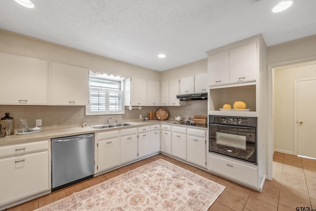 kitchen featuring tasteful backsplash, a sink, under cabinet range hood, black appliances, and light tile patterned flooring