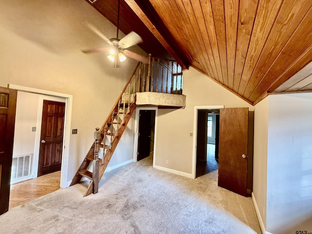 unfurnished living room featuring high vaulted ceiling, beamed ceiling, ceiling fan, wood ceiling, and light carpet