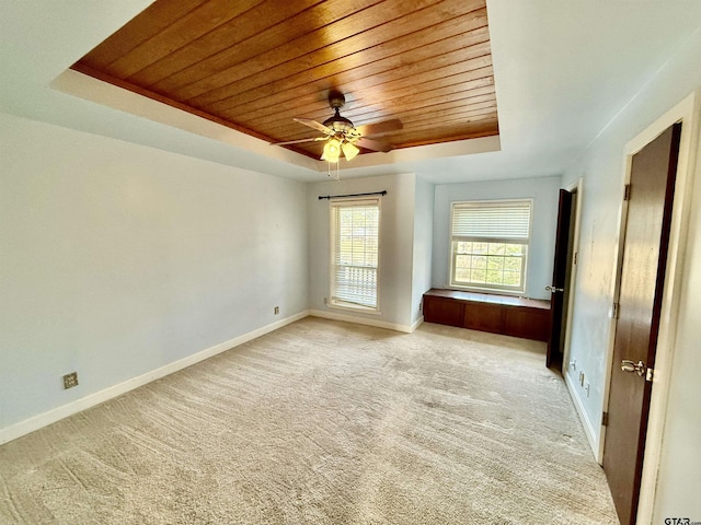 carpeted spare room with a tray ceiling, wood ceiling, and ceiling fan