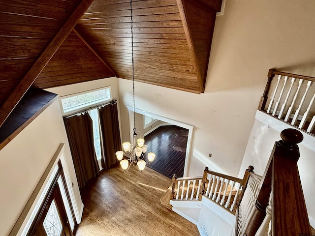 staircase featuring wood ceiling, high vaulted ceiling, a notable chandelier, hardwood / wood-style flooring, and beam ceiling